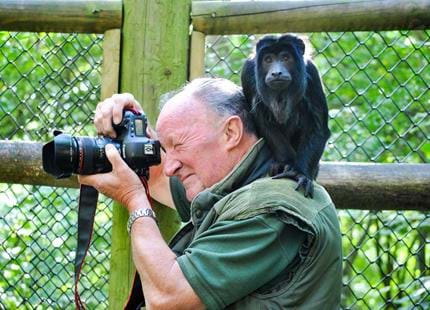 Dave Rolfe, resident photographer at Port Lympne Hotel & Reserve in Kent with a howler monkey