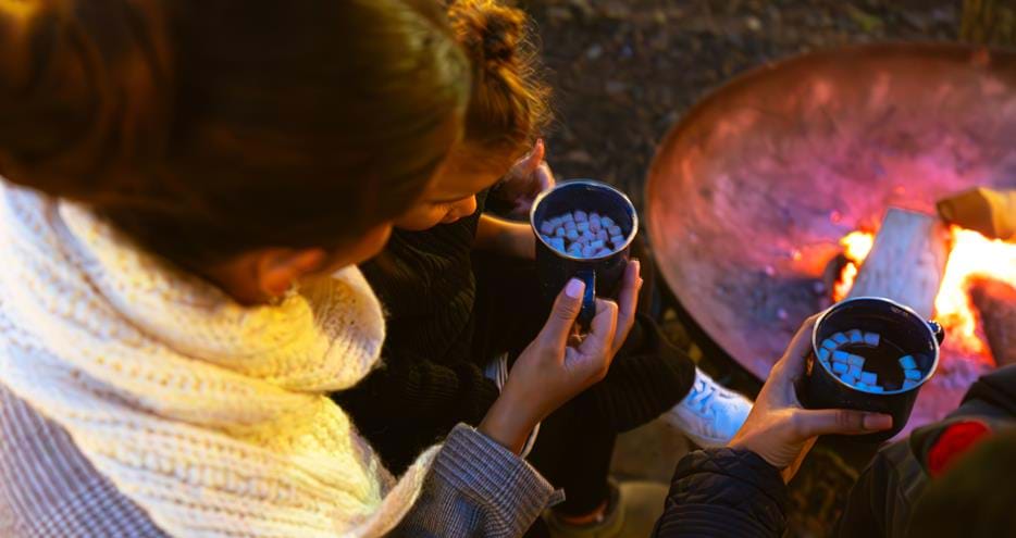 Drinking hot chocolate by the firepit at Pinewood glamping pods at Port Lympne Hotel & Reserve in Kent, UK
