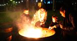 A family toasting marshmallows by the firepit at Pinewood glamping pods at Port Lympne Hotel & Reserve in Kent, UK