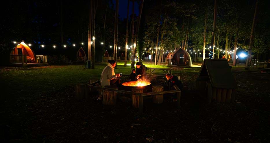Toasting marshmallows by the firepit at Pinewood glamping pods at Port Lympne Hotel & Reserve in Kent, UK
