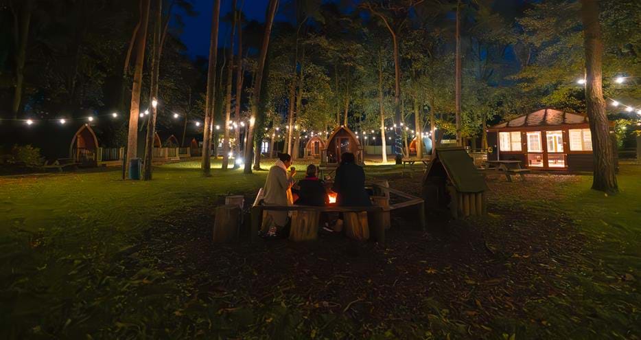 Toasting marshmallows by the firepit at Pinewood glamping pods at Port Lympne Hotel & Reserve in Kent, UK